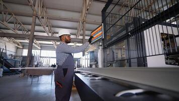 Indian Asian engineer sets up a production line at programmable CNC machine in window factory video