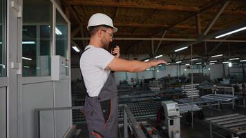 Foreman with walkie talkie giving commands to workers in PVC window factory video