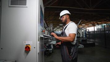 Industrial worker programmer sets up production line conveyor and gives commands via radio walkie talkie video