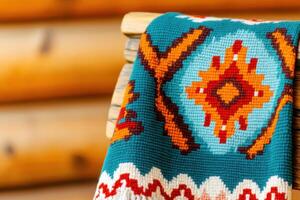 Colorful traditional Native American blanket with geometric patterns draped over a rustic wooden chair in a cozy setting photo