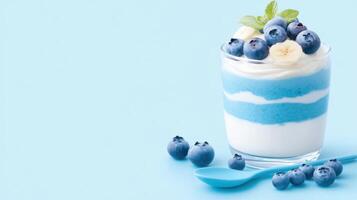 Delightful layered parfait featuring blue yogurt and fresh berries in an elegant glass setting with a matching spoon photo