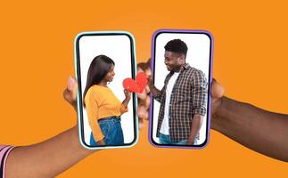 A couple joyfully engages in a chat via their smartphones, each holding a phone with a heart graphic on the screen. The background is bright and playful, reflecting their connection. photo