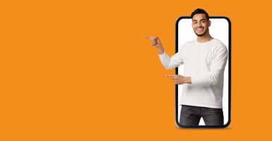 A man is actively engaging with a large smartphone screen, pointing to various applications. The vibrant background enhances the focus on technology and modern communication. photo