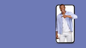 A person is happily pointing at a smartphone with a large screen, showcasing the ease of communication and social media interaction through advanced technology. The background features an empty space. photo