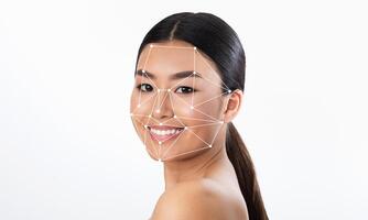 A young woman smiles towards the camera while facial recognition technology highlights her features with a geometric overlay. The background is plain, emphasizing her expression and the technology. photo