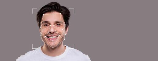 A man with a charming smile is central, showcasing advanced facial recognition technology. The background is blank, emphasizing the facial features and identification processes used. photo