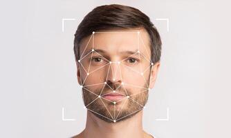 Advanced facial recognition technology scans a person's face for identification. The subject stands against a plain background, emphasizing the technological elements in action. photo