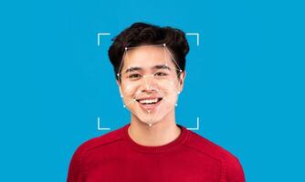 A young man with a cheerful expression poses against a vibrant blue background. Facial recognition markers highlight his features, showcasing advanced identification technology in use. photo