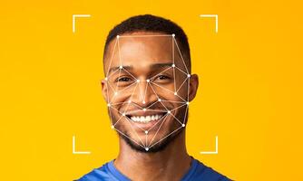 A young man with a bright smile is featured against a vibrant yellow background. Facial recognition technology overlays are visible, highlighting his facial features. photo