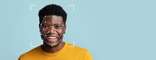 A young man with a bright smile is shown against a solid light blue background. Facial recognition technology overlays geometric patterns on his features, indicating identification. photo