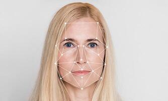 A woman with long blonde hair appears in a facial recognition process. Geometric patterns overlay her face, illustrating the use of identification technology in a modern context. photo