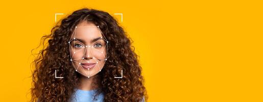 A woman with curly hair is shown against a bright yellow background. Her face features facial recognition markers, highlighting the use of identification technology for analysis and recognition. photo