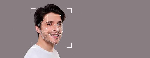 A young man is smiling, his face is highlighted by facial recognition points. This technology enhances identification in various applications, emphasizing modern advancements in personal security. photo