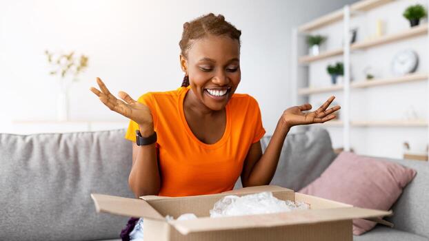 en línea entrega, remoto compras concepto. positivo negro mujer desembalaje cartulina parcela, satisfecho con exitoso compra a hogar. alegre hembra cliente recepción orden desde Internet Tienda foto