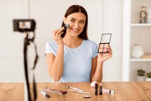 Girl Creating Beauty Blog Making Teaching To Make Makeup And Use Cosmetics Sitting At Camera At Home. Selective Focus photo