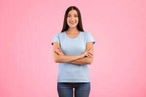 Portrait of happy casual lady smiling, looking at camera and posing with folded arms isolated over yellow studio background. Confident caucasian woman crossing hands, expressing positive emotions photo