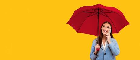 Nice Conversation. Portrait of cheerful lady talking on cell phone, holding umbrella, looking up at copy space photo