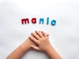 Childs hands with colorful letters manic on white background photo