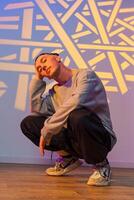 A young man sits with his legs crossed in a squat, with a projection of white lines and shapes behind him photo