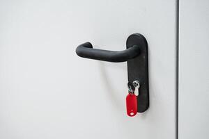Door handle with a red key visible, showcasing a simple and functional design on a plain wall photo