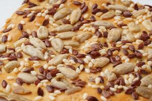 Delicious crispy snack topped with a blend of seeds and nuts on a white plate in bright lighting photo