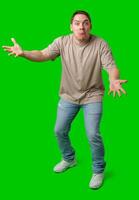 Young man in casual clothing stands with open arms against a vibrant green background photo