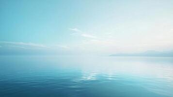 Tranquil turquoise ocean reflecting pastel sunrise sky with misty mountain range in background, creating serene and minimalist seascape photo