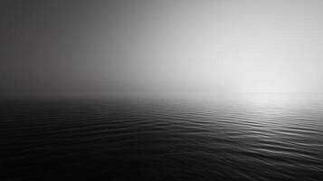 Minimalist black and white seascape featuring calm water with a light fog covering the horizon photo