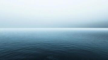 Minimalist landscape showing calm water surface merging with misty sky on a foggy day photo