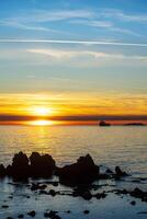 Sunset over the sea with container ship and rocks in the backlight photo