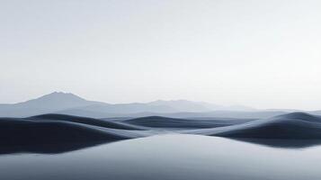Minimalist landscape featuring smooth, dark hills reflected in still water, with misty mountains visible in the distance under a pale sky photo