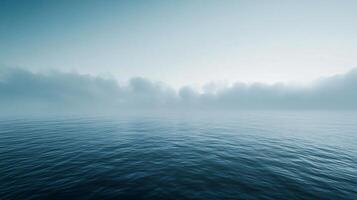Low clouds are hovering over a calm dark blue sea creating a mysterious and moody atmosphere photo