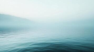 Minimalist landscape of a lake covered by fog at dawn with mountains in the background, creating a serene and peaceful atmosphere photo