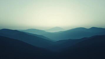 Soft light illuminates the peaks of a mountain range, creating a serene and minimalist landscape photo