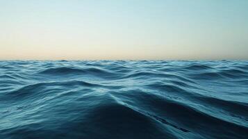 Soft ocean waves are creating a soothing texture under a clear sky during a beautiful sunset photo