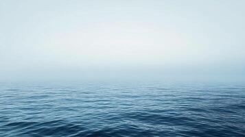 Tranquil blue ocean surface merging seamlessly with a misty sky, creating a serene and minimalist seascape photo