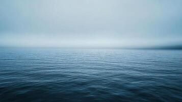 Calm ocean waters blend seamlessly with a misty sky, creating a tranquil and minimalist seascape photo