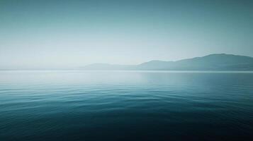 Serene morning mist hovering over a tranquil lake with mountains in the background photo