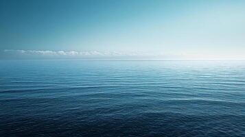 Tranquil ocean scene reflecting blue sky with distant clouds on horizon, creating peaceful and serene atmosphere photo