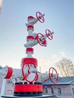 A pipe that is colored red and white and features numerous valves attached to it, suggesting its purpose might be related to gas or liquid transport in a building or industrial setting photo