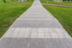 A beautiful brick walkway that leads to a grassy area in a lovely park photo