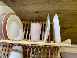 A beautifully crafted wooden dish rack that displays an assortment of plates, cups, and glasses arranged neatly on it, showcasing the importance of organized serveware in the kitchen photo