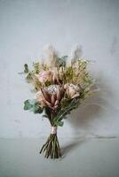 A beautiful bouquet of vibrant flowers is elegantly arranged and sitting on a sturdy table in front of a clean and bright white wall that enhances its colors and attractiveness photo
