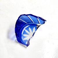 One piece of broken blue glass drinkware with sharp fragment edges isolated on square white floor background. photo