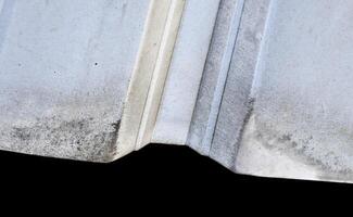 Close up dusty thin metal asbestos roof material object isolated on horizontal background. photo