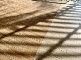 Sunlight and window shade on brown wooden flooring surface isolated on horizontal background. photo
