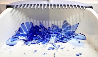 Group of broken blue cup glass with sharp fragment pieces isolated on horizontal white dustpan surface background from front view. photo