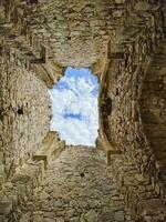A sturdy stone wall with a beautifully designed window offers a breathtaking view of the blue sky, inspiring reflections on the rich history and charm of the ancient ruins photo