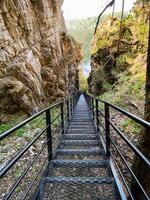 There is a beautifully constructed set of stairs that ascends gracefully up to a high cliff situated in the breathtaking depths of a canyon, creating a stunning view of the landscape photo