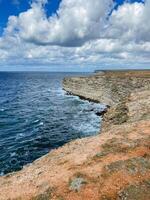 A stunning, towering cliff majestically looms over the vast ocean on a moody, overcast day, creating a breathtakingly beautiful view that captivates all who gaze upon it with wonder photo